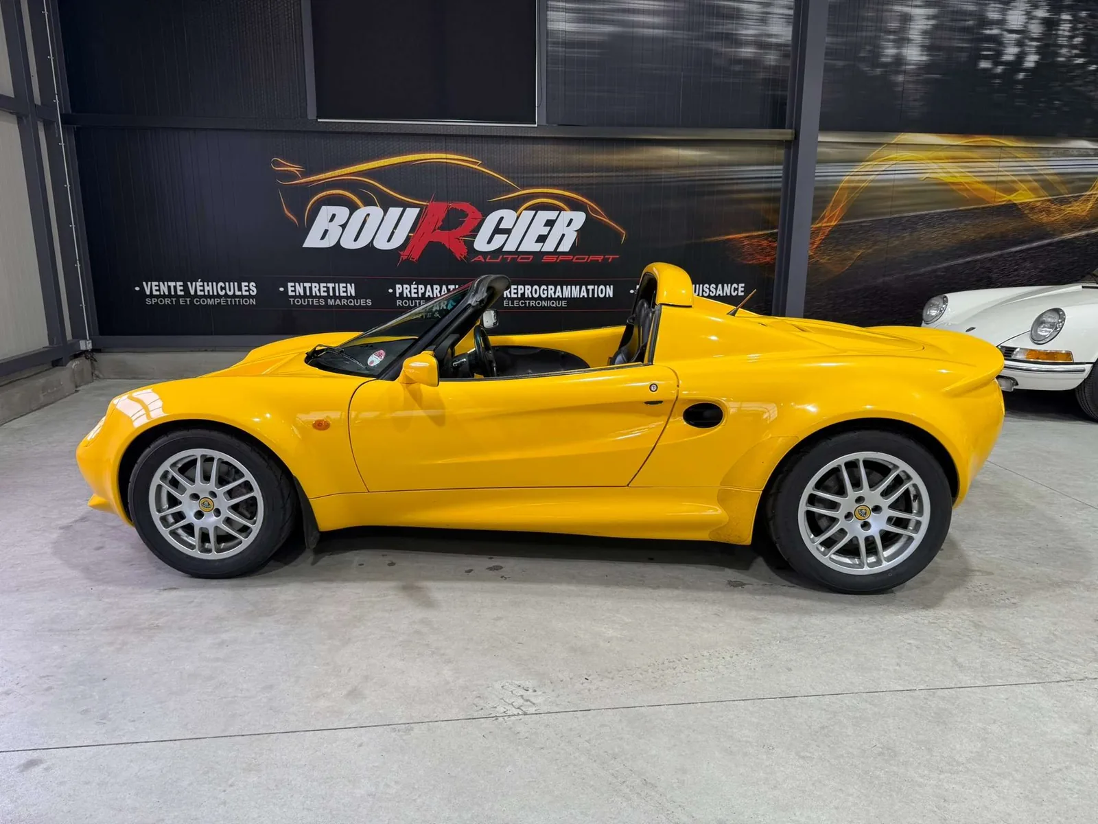 Lotus Elise S1 jaune de trois quarts avant, carrosserie composite minimaliste et prises d'air latérales